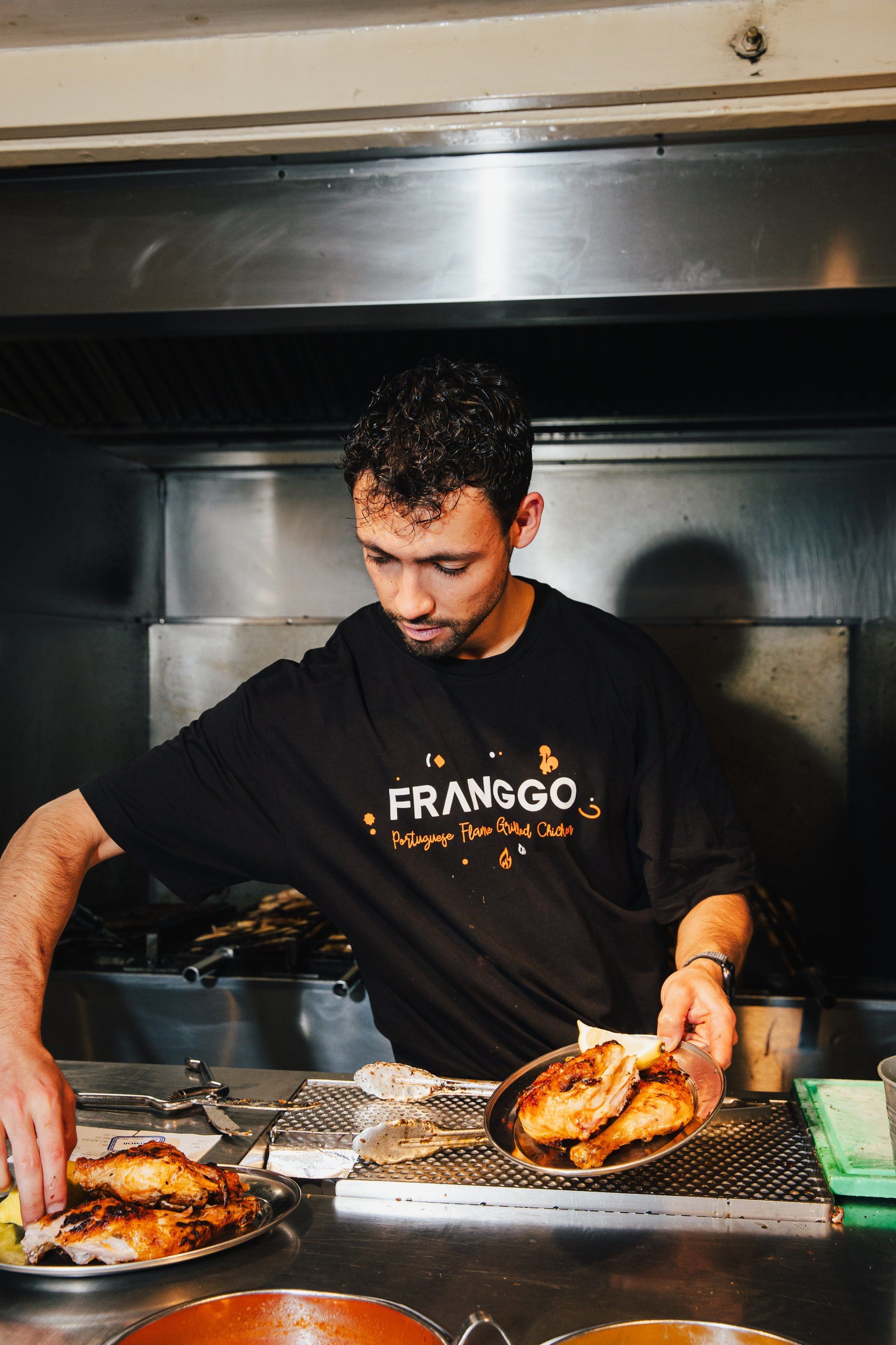 Een Franggo-kok schept kip op aan de grill