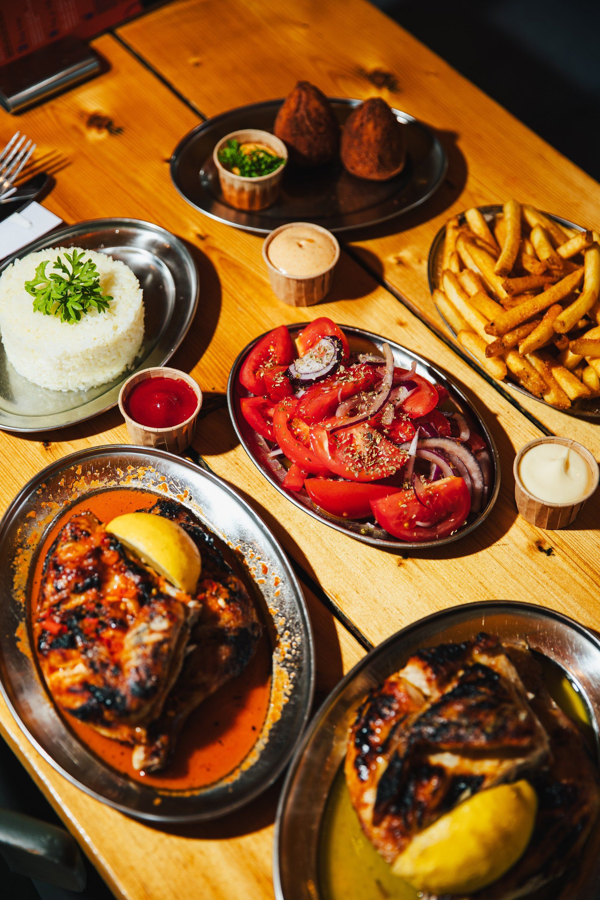 A Franggo table from above: flame-grilled chicken, rice, tomato salad, fries and coxinhas