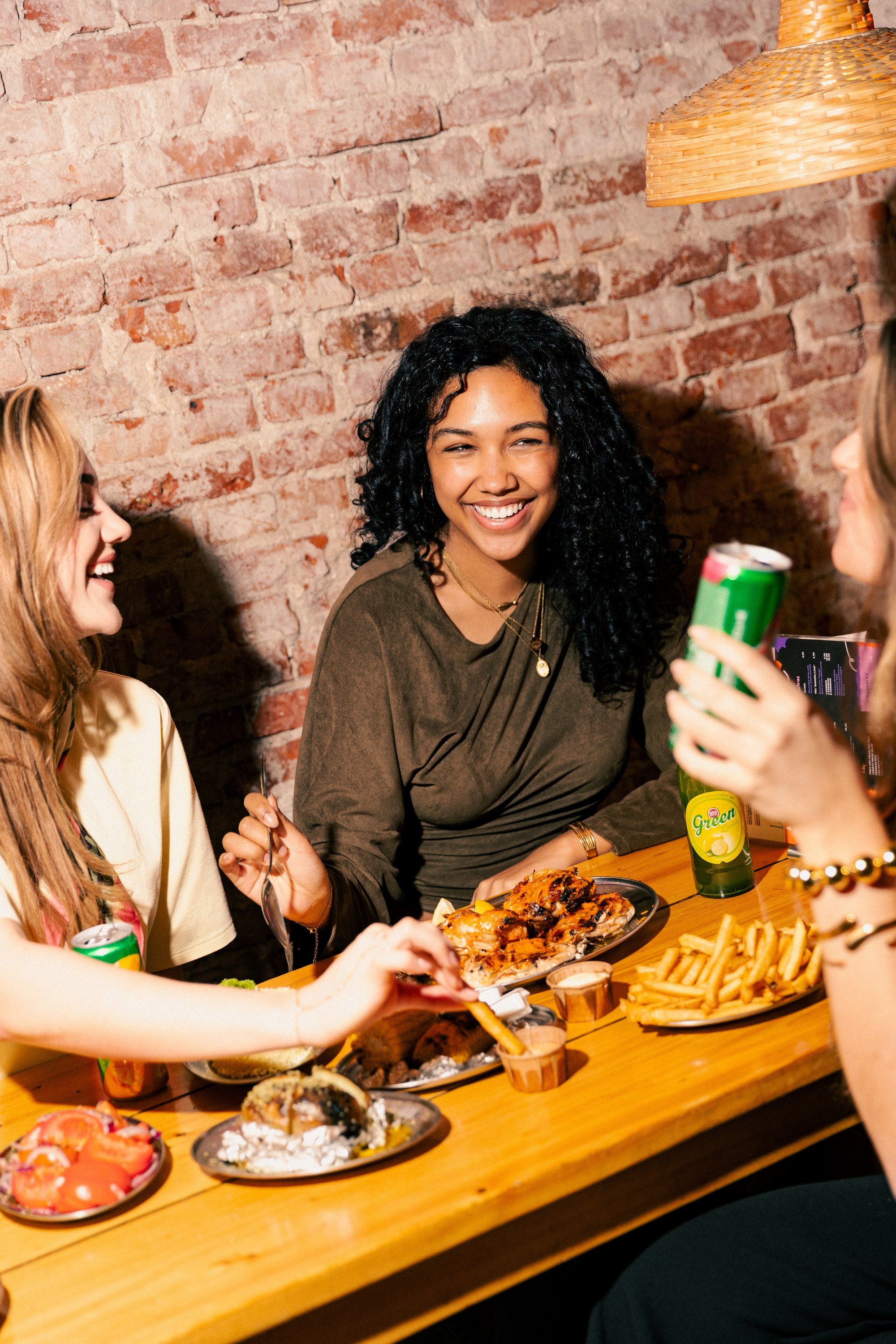 Three friends sharing chicken, corn and drinks at Franggo West