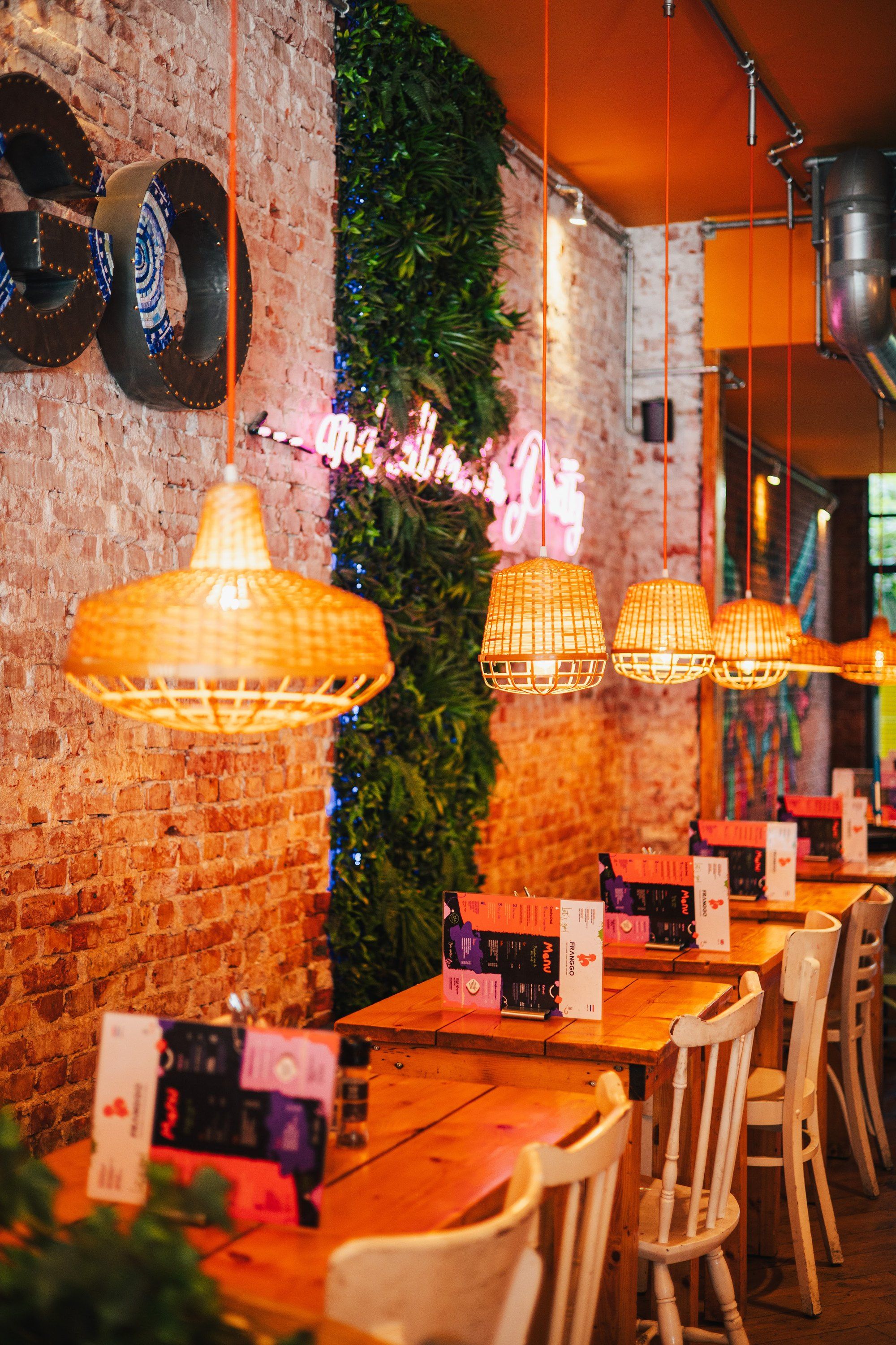De tafels van Franggo West met de groene wand en roze neon