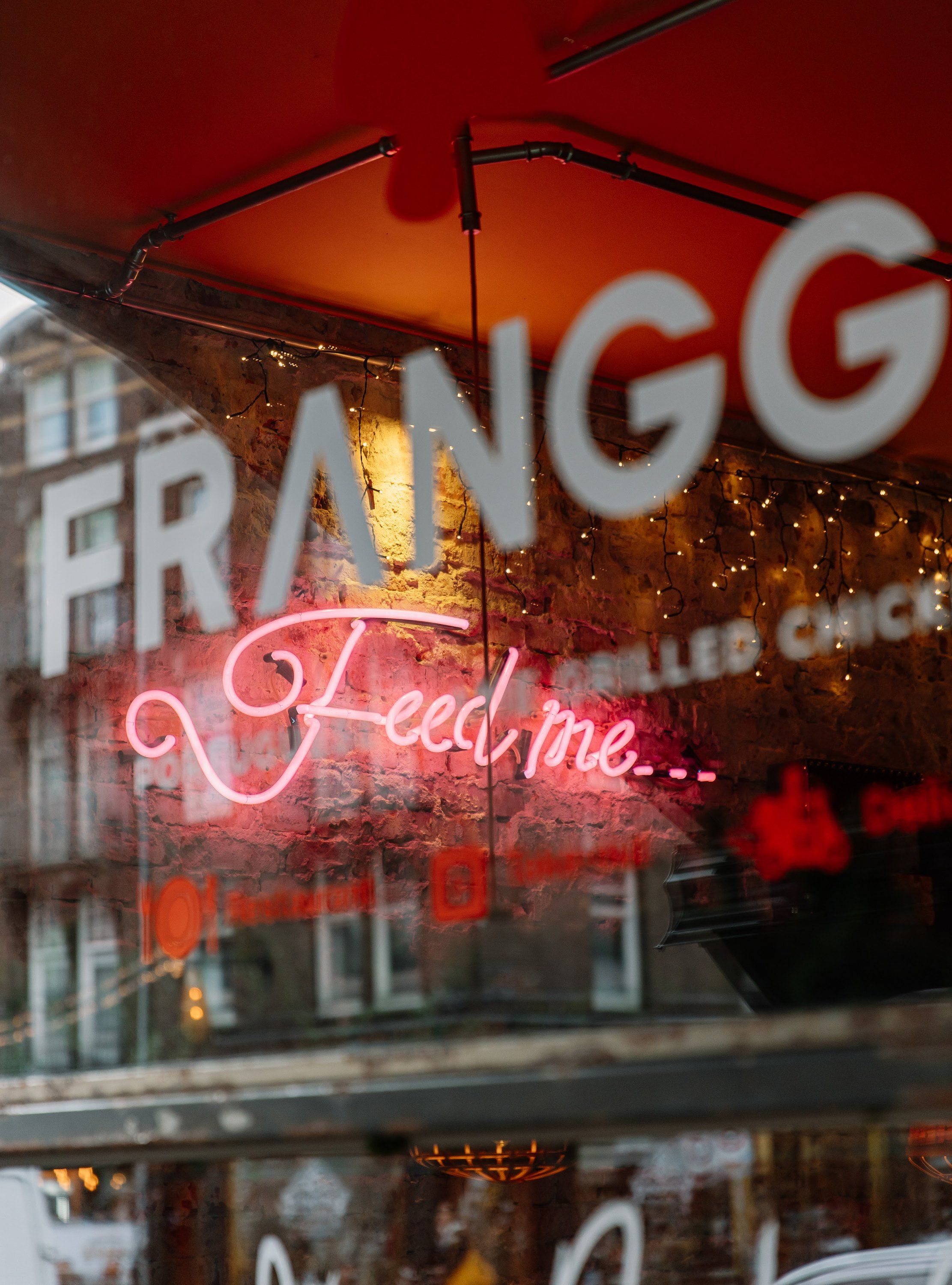Het raam van Franggo West met de neon “Feed me”